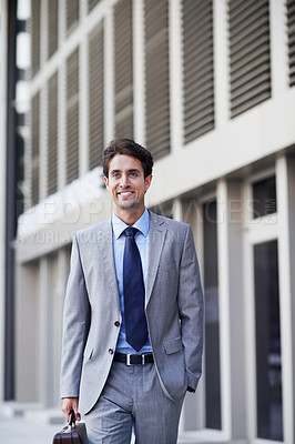 Buy stock photo A handsome businessman walking in the city central while carrying his briefcase