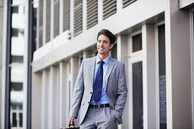Buy stock photo A handsome businessman walking in the city central while carrying his briefcase