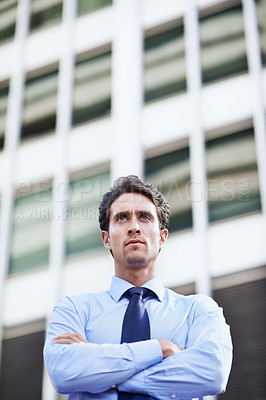 Buy stock photo A determined businessman standing in the city central with his arms folded