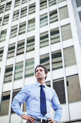 Buy stock photo A handsome businessman standing in the city central with his hands on his hips