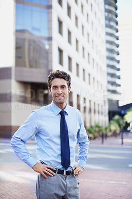 Buy stock photo A handsome businessman standing in the city central with his hands on his hips