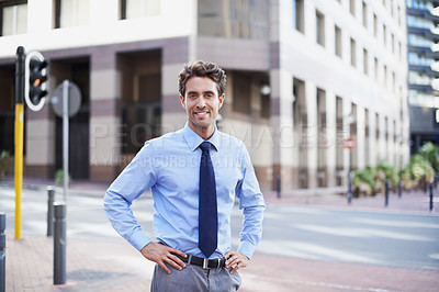 Buy stock photo A handsome businessman standing in the city central with his hands on his hips