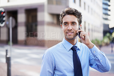 Buy stock photo A handsome businessman on his cellphone while in the city central