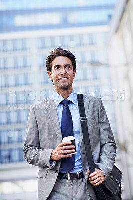 Buy stock photo A handsome businessman walking in the city central while having a cup of coffee