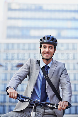 Buy stock photo A handsome businessman riding his bicycle to work in the city central while wearing a bicycle helmet