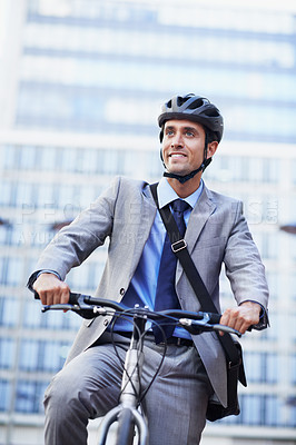 Buy stock photo A handsome businessman riding his bicycle to work in the city central while wearing a bicycle helmet