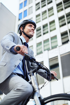 Buy stock photo A handsome businessman riding his bicycle to work in the city central while wearing a bicycle helmet
