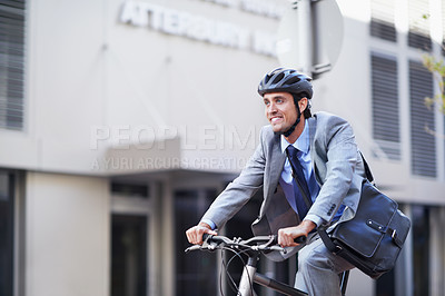 Buy stock photo A handsome businessman riding his bicycle to work in the city central while wearing a bicycle helmet