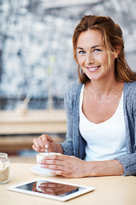 Buy stock photo Portrait of a woman sitting in coffee shop stirring her coffee with her touchscreen in front of her