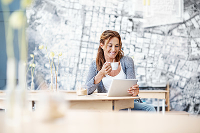 Buy stock photo A smiling beautiful woman at a coffee shop looking at her touchscreen and holding her coffee with copyspace