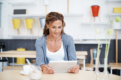 Buy stock photo A beautiful woman in a coffee shop looking at her touchscreen with copyspace