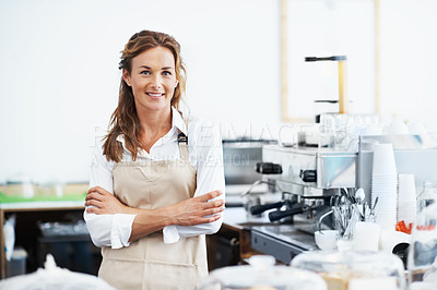 Buy stock photo Portrait of a smiling pretty barista standing next to a coffee machine with her arms crossed