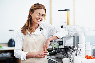 Buy stock photo Portrait of a smiling  pretty barista leaning against a coffee machine