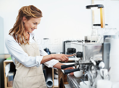 Buy stock photo A pretty barista using the coffee machine