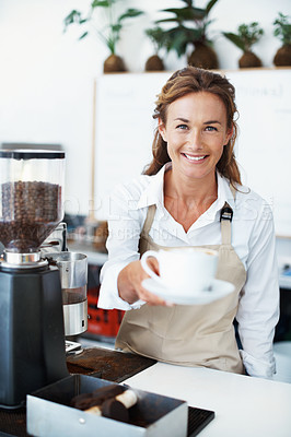 Buy stock photo Portrait of a smiling barista handing you a cup of coffee