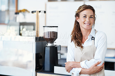 Buy stock photo Portrait of a smiling barista with her arms crossed standing next to a coffee machine