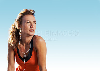 Buy stock photo Young woman weraing sports clothes listening to music while looking into the distance