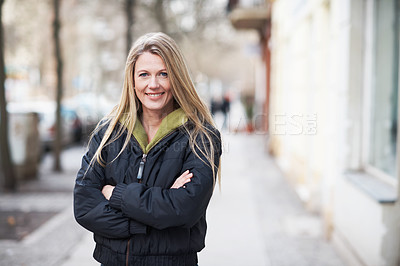 Buy stock photo Portrait of a smiling woman standing on the sidewalk with her arms folded