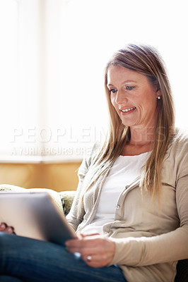 Buy stock photo A beautiful woman working on her digital tablet at home