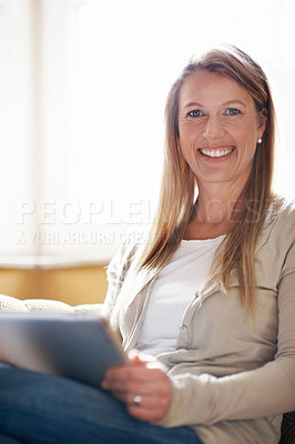 Buy stock photo A beautiful woman working on her digital tablet at home