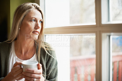 Buy stock photo A pensive woman looking out the window while holding a cup of coffee with copyspace