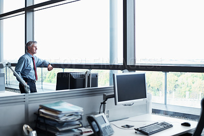 Buy stock photo Shot of a senior businessman looking out the window of his office