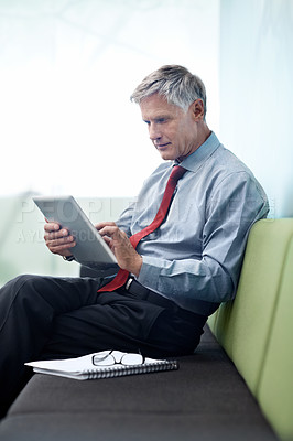 Buy stock photo Shot of a senior businessman using his tablet indoors