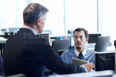 Buy stock photo Shot of two businessmen discussing something at workstation