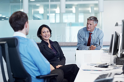 Buy stock photo Shot of three businesspeople discussing something at a workstation