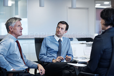 Buy stock photo Shot of three businesspeople discussing something at a workstation