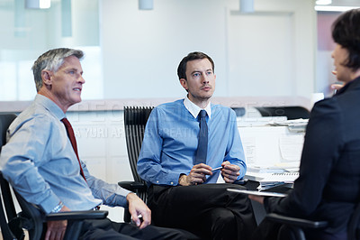 Buy stock photo Shot of three businesspeople discussing something at a workstation