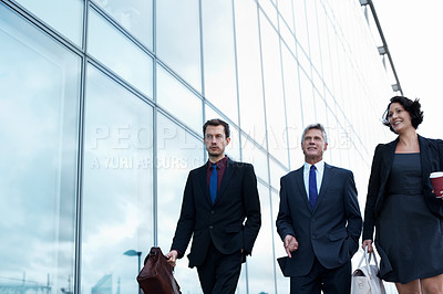 Buy stock photo Shot of three businesspeople walking beside an office building