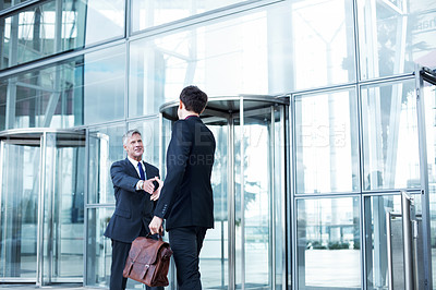 Buy stock photo Shot of two businessmen shaking hands at the entrance of a building