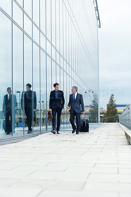 Buy stock photo Shot of two businessmen walking and talking next to an office building