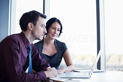 Buy stock photo Shot of two young businesspeople looking at a laptop together
