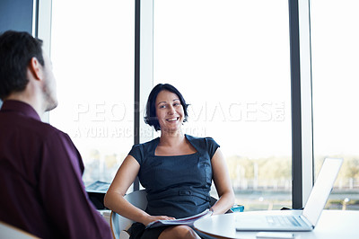 Buy stock photo Shot of two young colleagues sitting together around a table