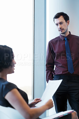 Buy stock photo Shot of a young businesswoman reading a report to her colleague