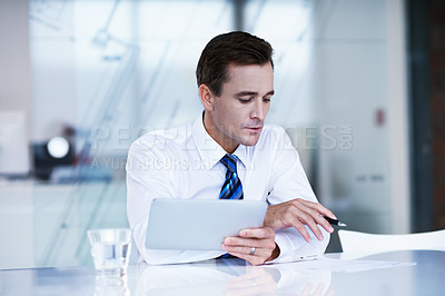Buy stock photo Shot of a businessman sitting in an office using a digital tablet