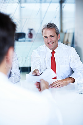 Buy stock photo Over the shoulder shot of a group of businesspeople discussing documents in an office