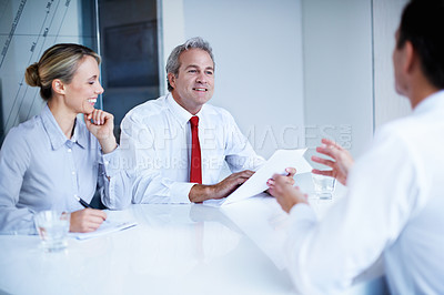 Buy stock photo Over the shoulder shot of a group of businesspeople discussing documents in an office