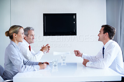 Buy stock photo Shot of a group of businesspeople sitting at a table talking
