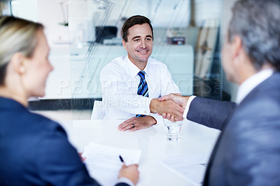 Buy stock photo Shot of two businesspeople shaking hands while having a meeting in an office