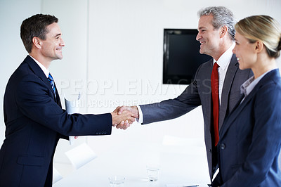Buy stock photo Shot of two businesspeople shaking hands in an office