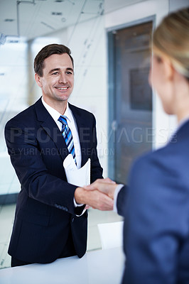 Buy stock photo Shot of two businesspeople shaking hands in an office