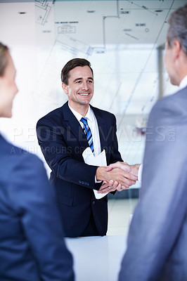 Buy stock photo Over the shoulder shot of a group of businesspeople shaking hands in an office