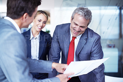 Buy stock photo Over the shoulder shot of a group of businesspeople discussing documents in an office
