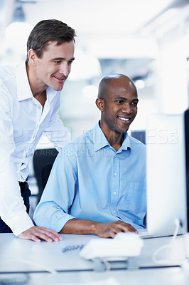 Buy stock photo Shot of two office workers talking over a desktop computer in an office
