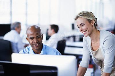 Buy stock photo Shot of two office workers talking over a desktop computer in an office