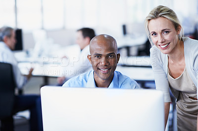 Buy stock photo Portrait of two office workers talking over a desktop computer in an office