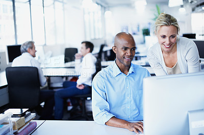 Buy stock photo Shot of two office workers talking over a desktop computer in an office